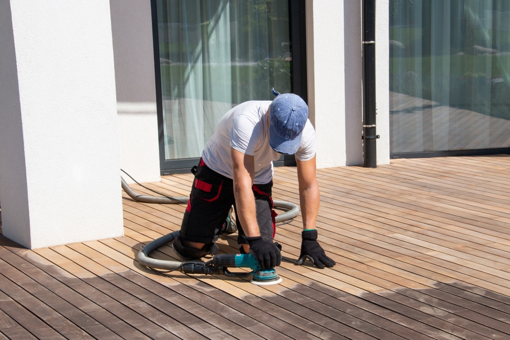 man sanding wood deck to prepare it for staining